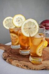 Three glasses of iced tea with lemon slices on a wooden board