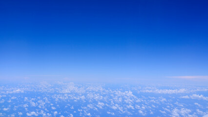 Horizontal gradient blue sky with white fluffy clouds