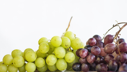 Close up of a bunch of white and red or purple grapes. Fresh bunches of green and blue grapes on the wooden table, isolated on white background. Healthy fruits concept. Copy space. Selective focus.