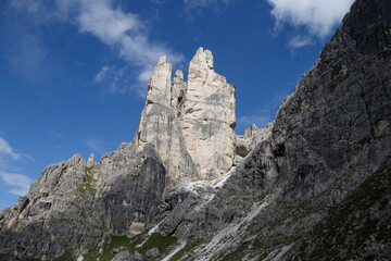 Massive, impressive mountains tower into a blue summer sky, showcasing the grandeur and beauty of the alpine landscape.