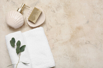 Clean soft towel, bottle of liquid soap and plant on grunge background