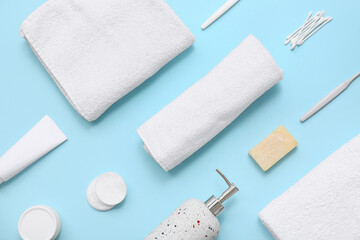 Composition with clean soft towel and different bath supplies on blue background, closeup