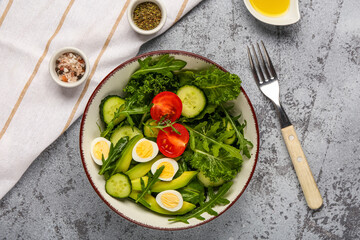 Bowl with healthy salad with quail eggs, tomato, avocado and cucumber on grunge background