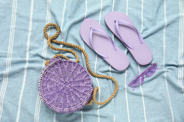 Flip flops with straw bag and sunglasses on textile background