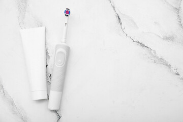 Electric toothbrush and paste on marble background