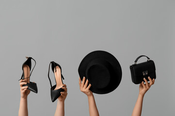 Female hands with bag, cap and heeled shoes on grey background