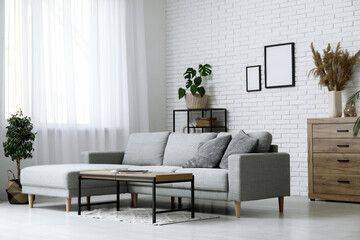 Stylish interior of living room with comfortable sofa, coffee table and houseplant