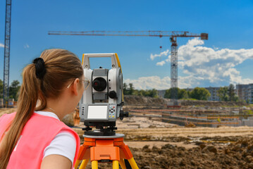 Woman surveyor performs work at a construction site. Geodetic work using theodelite