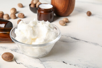 Fototapeta premium Glass bowl of shea butter and nuts on white background