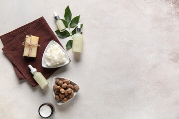 Bowl of shea butter with bottles of cosmetic oil, soap bar and nuts on white background