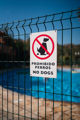 A No Dogs sign in Spanish and English on a fence surrounding a pool, ensuring a pet-free zone for...