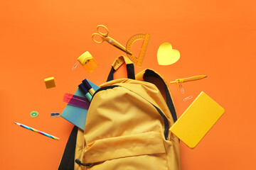 Backpack and books with different school stationery flying on orange background