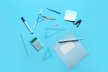 Books with different school stationery flying on blue background