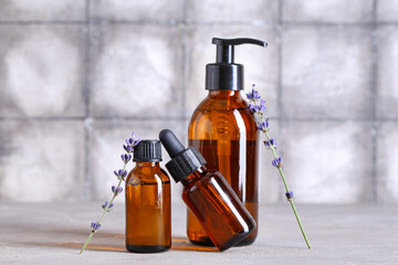 Bottles of lavender essential oil and flowers on grunge background, closeup