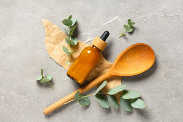 Wooden spoon, crumpled paper and bottle of eucalyptus essential oil on grunge background