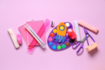 Paper rocket with different school stationery on pink background