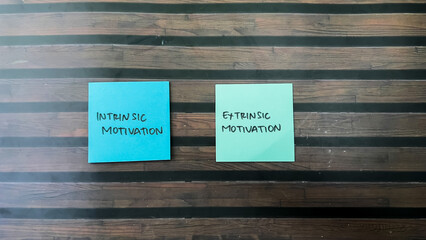 Concept of Intrinsic Motivation or Extrinsic Motivation write on sticky notes isolated on Wooden Table.