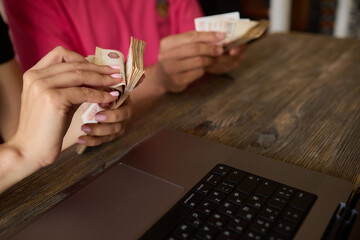 A person is working at a desk with a laptop, managing money for financial planning