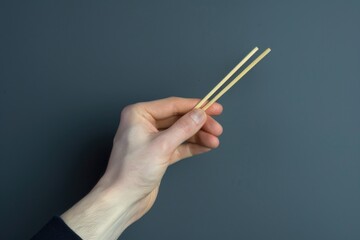 A person grasping a pair of chopsticks, ready for an Asian-inspired meal or cultural event