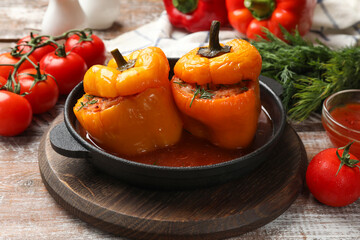 Tasty stuffed peppers in pan and products on wooden rustic table, closeup