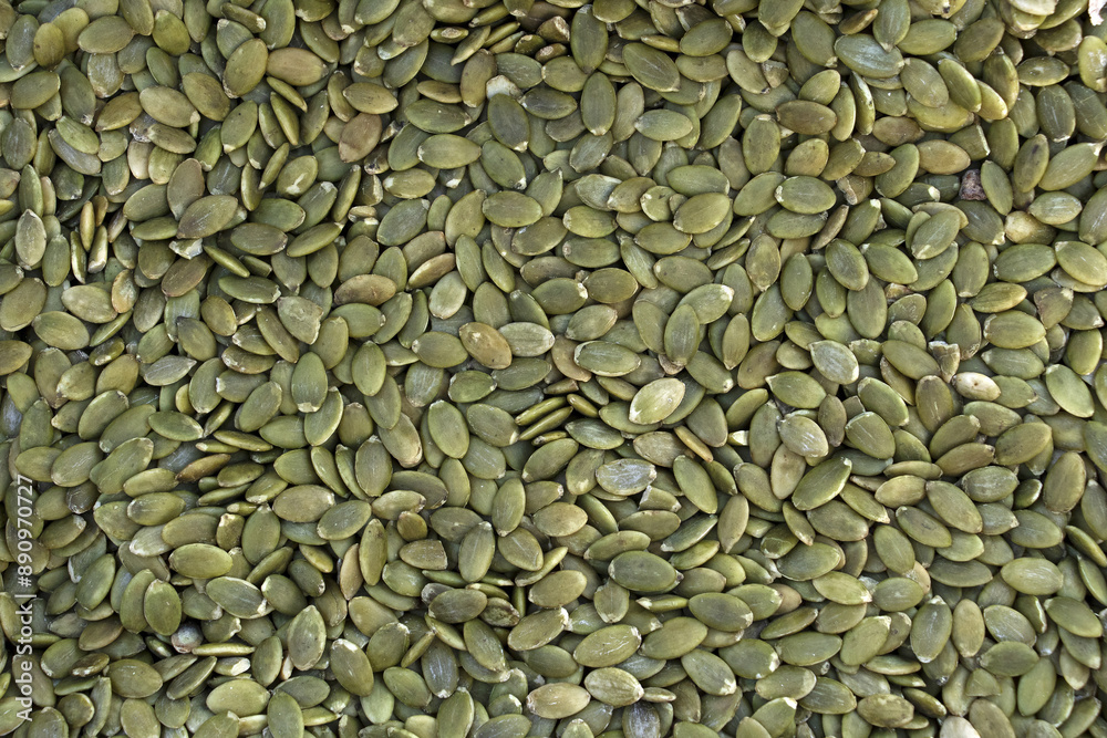 Wall mural close up and top angle view of stacked dried green pumpkin seeds for sale in a traditional market, s