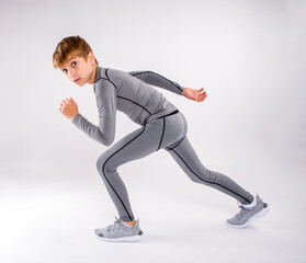 Young preteen male boy running track looking at camera in studio wearing compression uniform