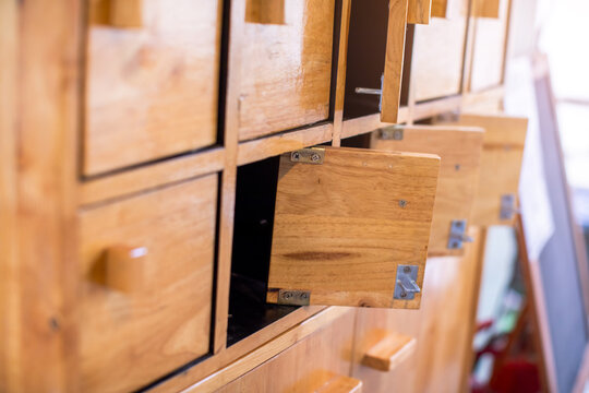 Close-up of a hand opening traditional wooden locker compartments or small wooden drawers. Vintage style furniture and storage concept.