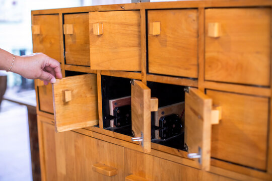 Close-up of a hand opening traditional wooden locker compartments or small wooden drawers. Vintage style furniture and storage concept.