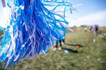 Selective focus on a pom-pom streamer with defocused child running in the background 
