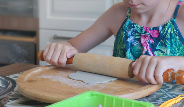Teenage girl molding clay with rolling pin at home. Hobbies and tools. Creativity for children, education.