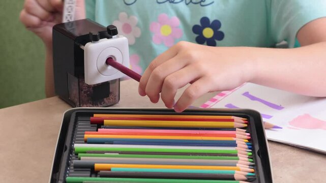 Teenage girl sharpening colored pencil in mechanical desk sharpener. Art and hobbies. Drawing tools. 