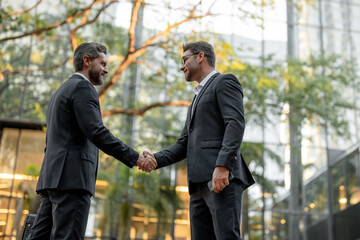 Two businessmen shaking hands outdoors. Shaking hands. Management strategy. Handshake between two...