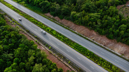 Aerial view of countryside asphalt road with car and green forest. Drive on the road between green forests.