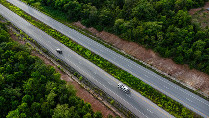 Aerial view of countryside asphalt road with car and green forest. Drive on the road between green forests.