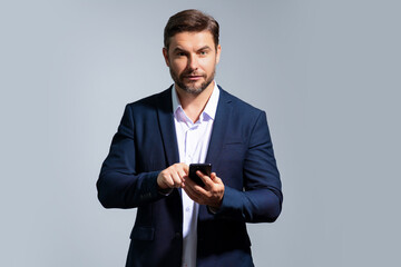 Handsome business man talking on phone. Business man in suit using smart phone isolated over studio background. Portrait of cheerful guy using cell phone, browse social media on phone.