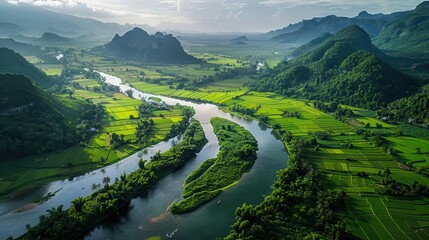Fototapeta premium Stunning aerial view of a winding river surrounded by lush green mountains and fertile fields under a clear blue sky.