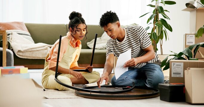 Couple, people and assemble table with document for instructions and tips in new home. House, relationship and boxes for moving in with diy, furniture and ownership in living room for renovations