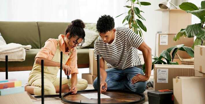 Couple, people and assemble table with manual for instructions and tips in new home. House, relationship and boxes for moving in with diy, furniture and ownership in living room for renovations