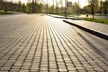 The morning sun shines on the paving slabs in the park