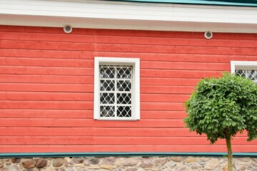 Window with bars on the wall of a red wooden house