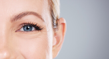 Naklejka premium Woman, portrait and makeup with blue eyes in skincare, cosmetics or optometry on a gray studio background. Closeup of female person or model with sight, eyelash or retina for mascara on mockup space