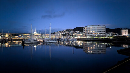 Night time in harbour marina with yachts and apartment  lights reflecting in water in capital city of Wellington, New Zealand Aotearoa