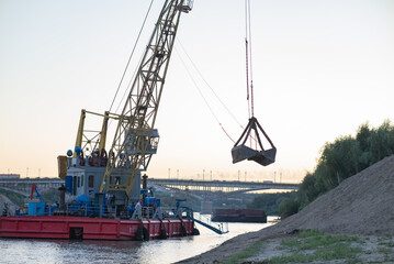 Barge loading sand by the crane. River in mountain region in Vietnam