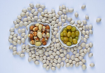 Close up and top angle view of stacked raw and roasted ginkgo seeds on two dish with others on white floor, South Korea
