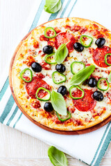 Pizza with salami, jalapeno pepper and black olives. Home made food. Concept for a tasty and hearty meal. Close up.