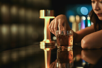 Close up shot sad young woman with glass of whiskey at bar counter