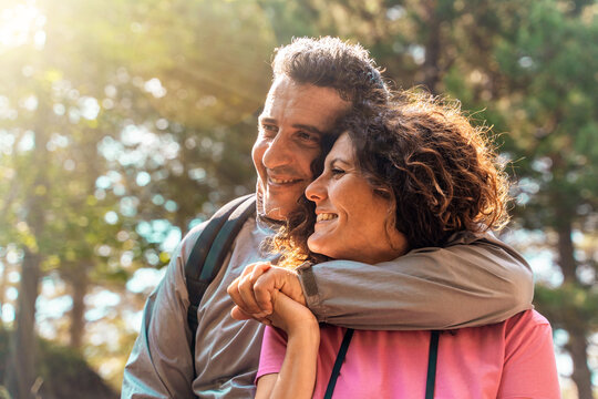 Authentic middle aged couple embracing and smiling in nature, romantic relationship lifestyle portrait