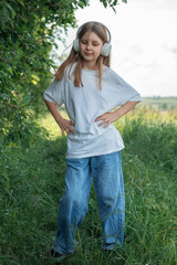 A child  with headphones listening to music and dancing in the park..