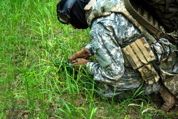 A soldier in camouflage sets a tripwire in the forest