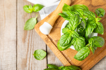 Fresh green basil in a mortar on a textured wooden background. Organic spices and herbs. Vegan. Fresh kitchen herbs. Fresh basil being made into pesto with mortar and pestle.Copy space. Place for text